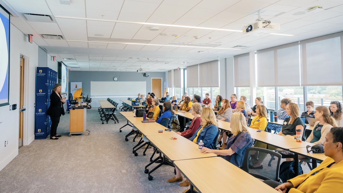 Attendee's in a classroom setting listening to a presentation by Alumni Dr. Robin Bartlett.