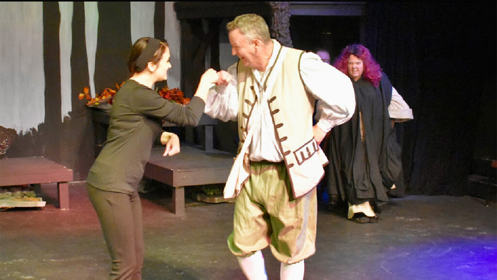 A Studio 1 actor in period dress fist bumps his sign language interpreter onstage.