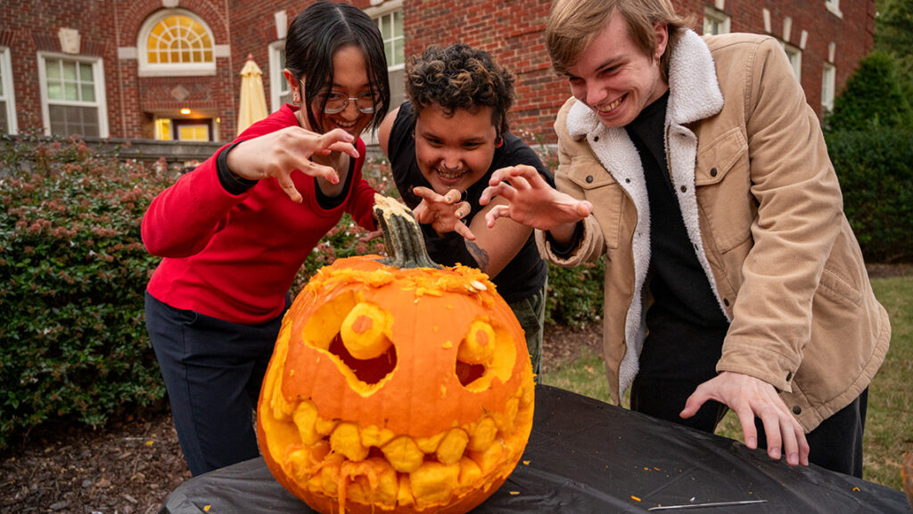 UNCG Residential College students hover menacingly over a jack-l-lantern.