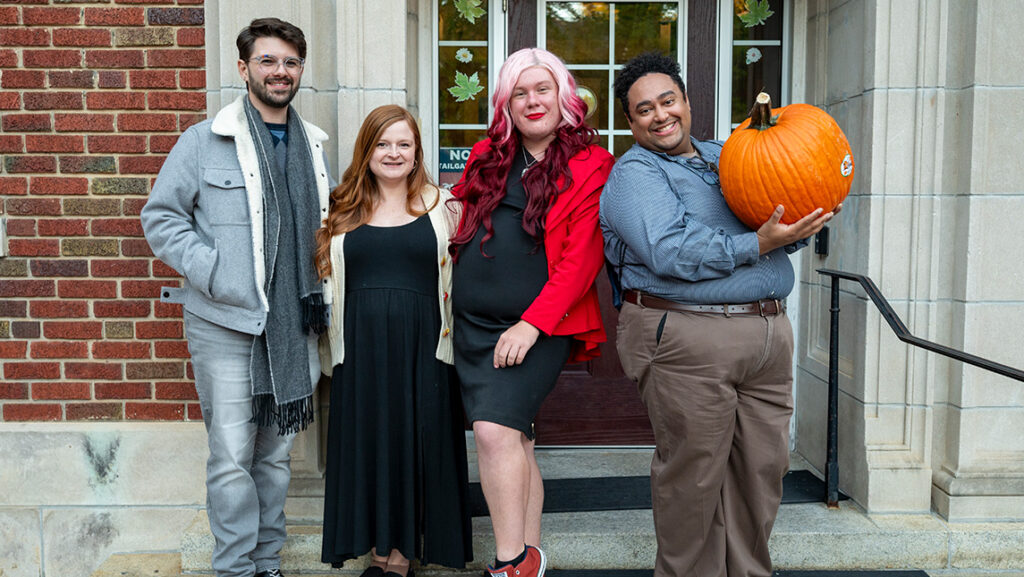 UNCG Residential Staff pose on the steps of a residence hall with a pumpkin.