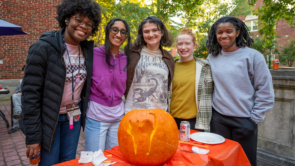 Five UNCG Residential College students pose behind their black cat jack-o-lantern.