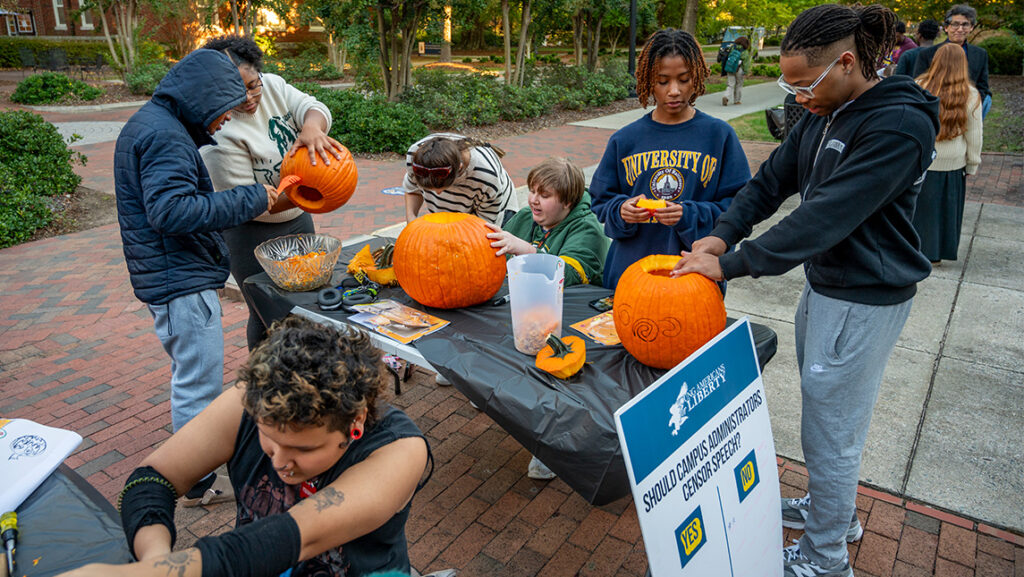 UNCG Residential College student busy carving jack-o-lanterns.