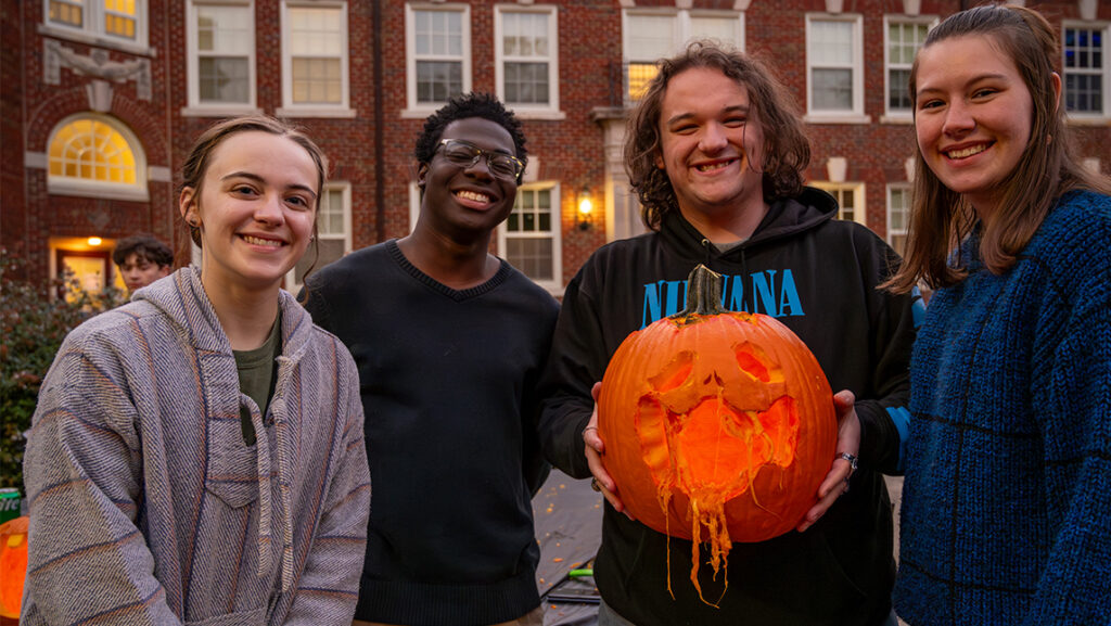 Four UNCG Residential College students show off their jack-o-lantern.