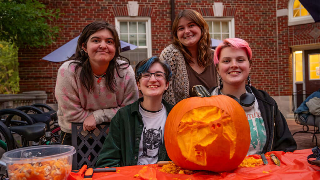 Four UNCG Residential College students pose next to their jack-o-lantern.