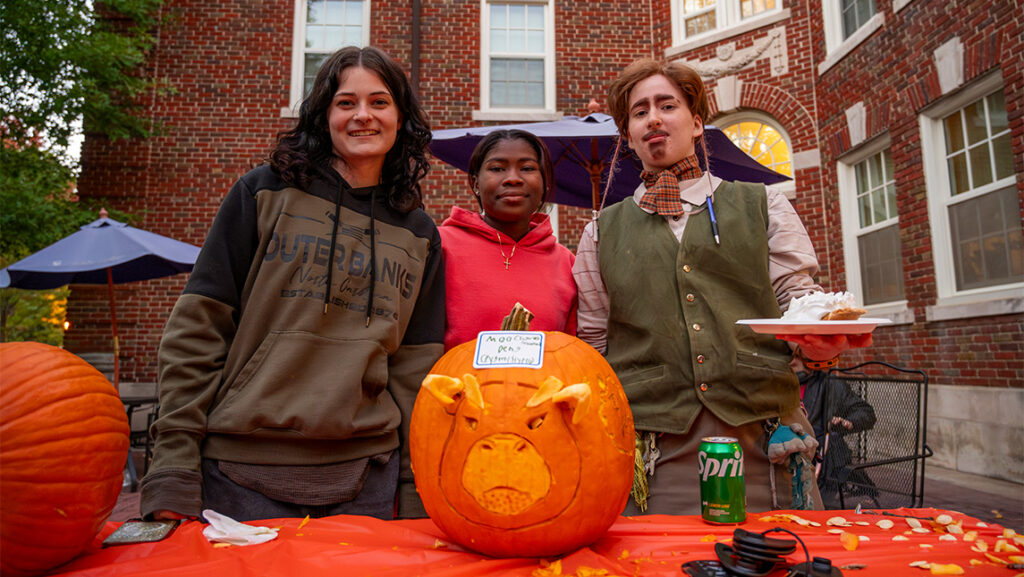 Three UNCG Residential College students show off their cow-themed jack-o-lantern.