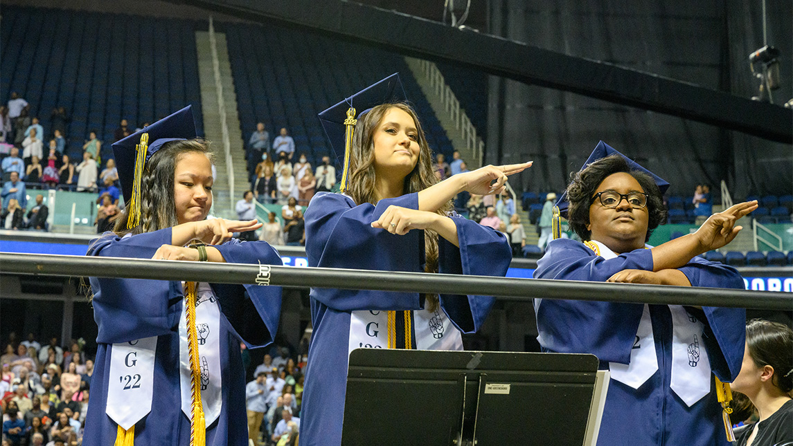 Three graduates of UNCG IDEAS do sign language during the National Anthem at Commencement.