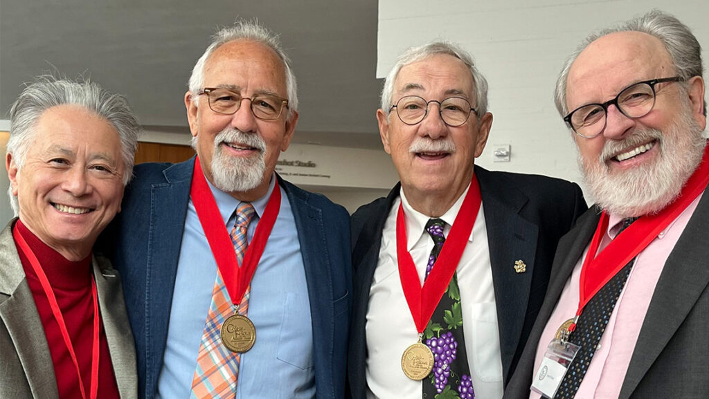 Four UNCG alumni wearing medals.