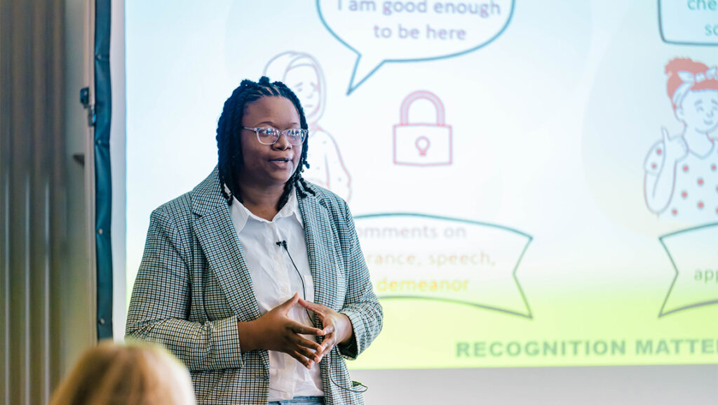 A UNCG student gives a presentation in front of a projected powerpoint.