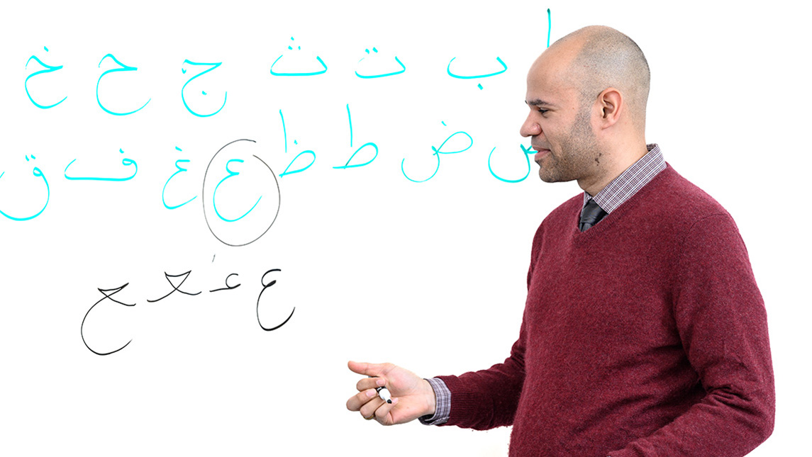 UNCG Professor Robert Wiley at a whiteboard with Arabic characters written on it.