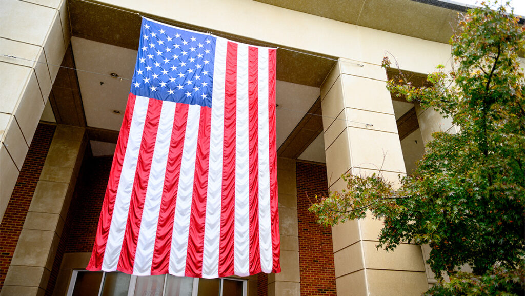 American flag hangs from a building at the UNCG campus.