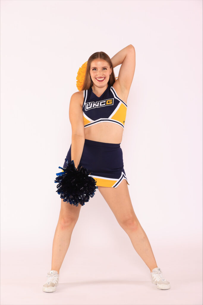 UNCG cheerleader poses with pompoms.