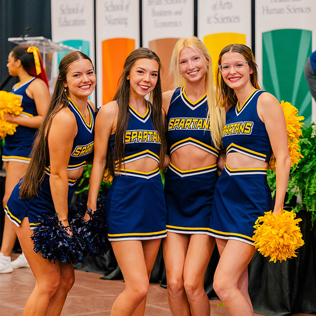 Group of UNCG cheerleaders pose together at a campus event.