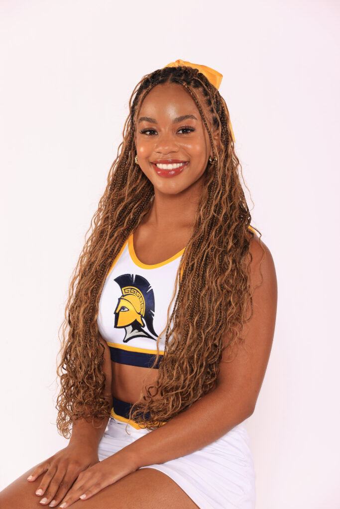 UNCG Cheerleader seated for a portrait.