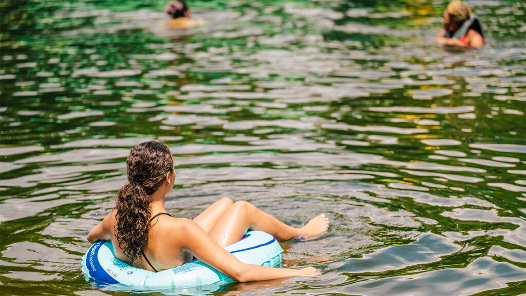 A UNCG student relaxes in an inner tube on Piney Lake.