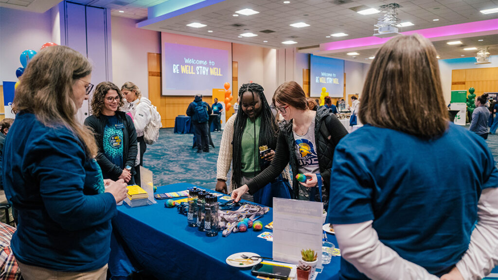 Students at UNCG look at wellness flyers and materials on a table.