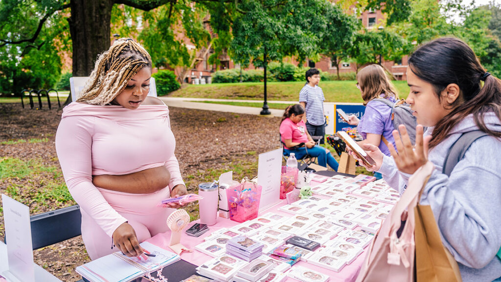 A UNCG student looks at small artwork boxes for sale.