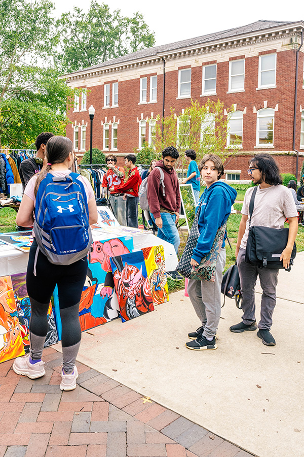 Students gather around artwork for sale in the UNCG student marketplace.