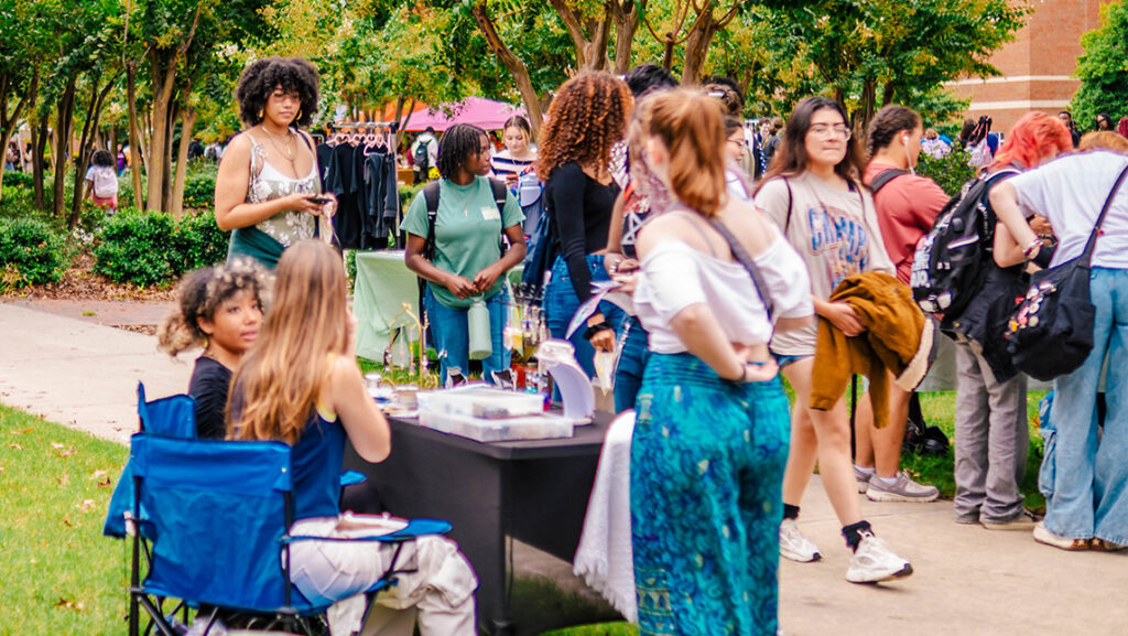 Students mill around the UNCG student marketplace outside on College Avenue.